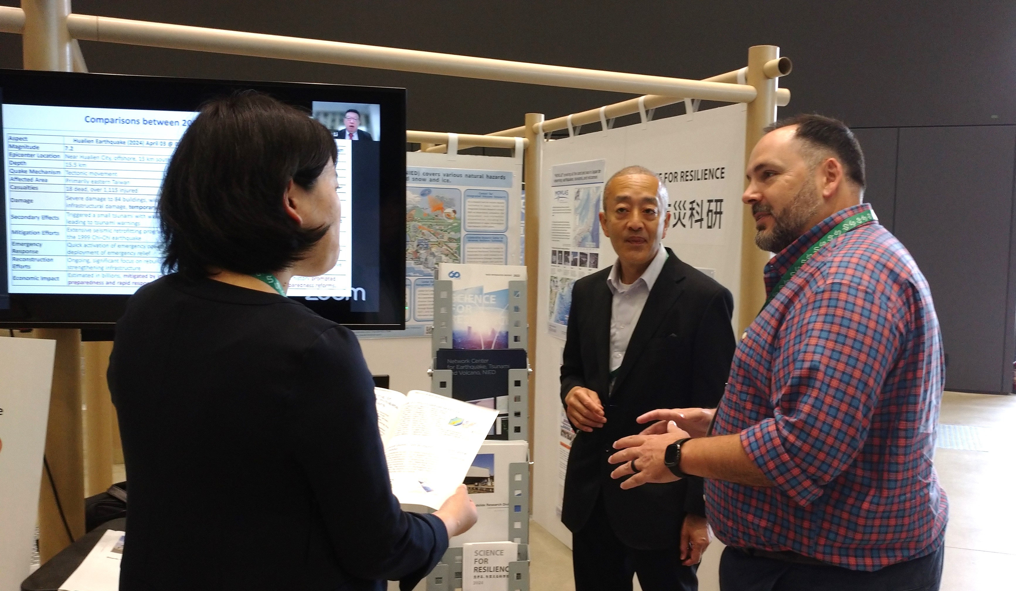 NIED team is explaining its research activities to a participant at the booth